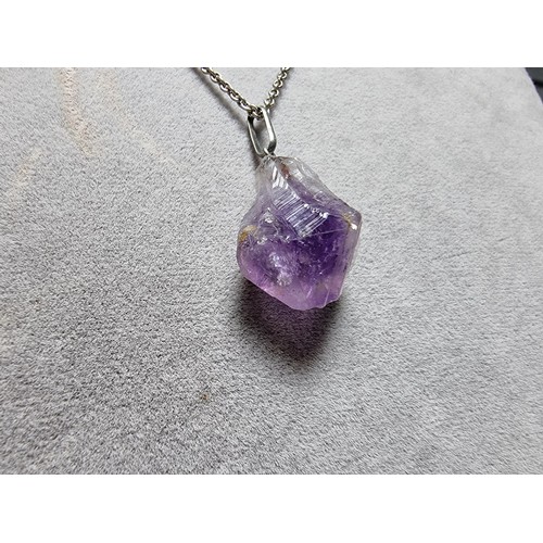 189 - A genuine amethyst rough cut pendant set on a long 23