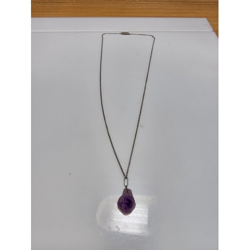 189 - A genuine amethyst rough cut pendant set on a long 23