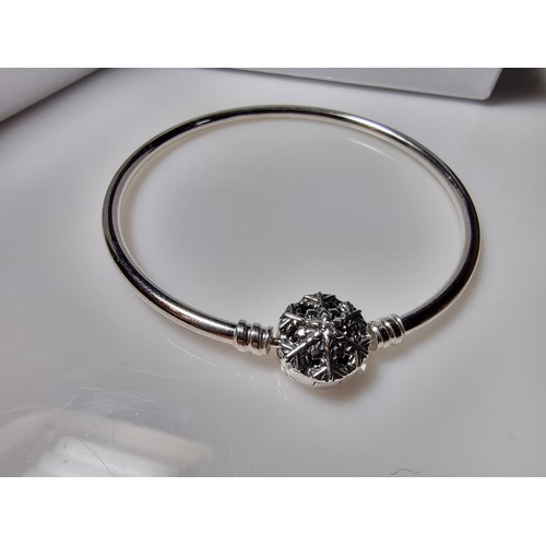 210 - A genuine Pandora 925 silver bangle with a snowflake charm inset with a crystal CZ stone, marked S92... 