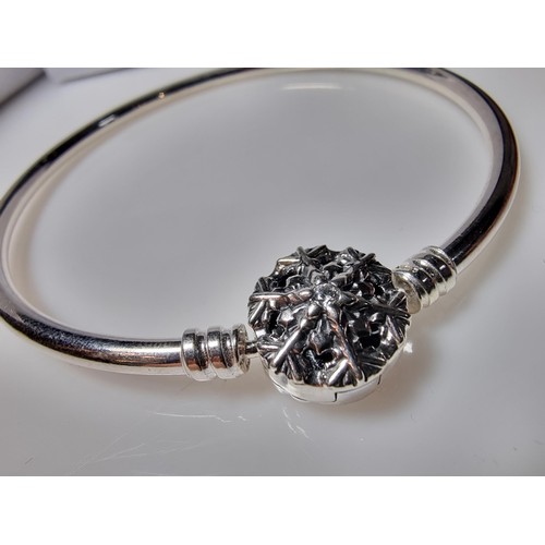 210 - A genuine Pandora 925 silver bangle with a snowflake charm inset with a crystal CZ stone, marked S92... 