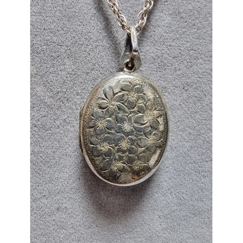 224 - A heavy 925 silver locket with an engraved flower design, complete with its glass inserts, set on a ... 