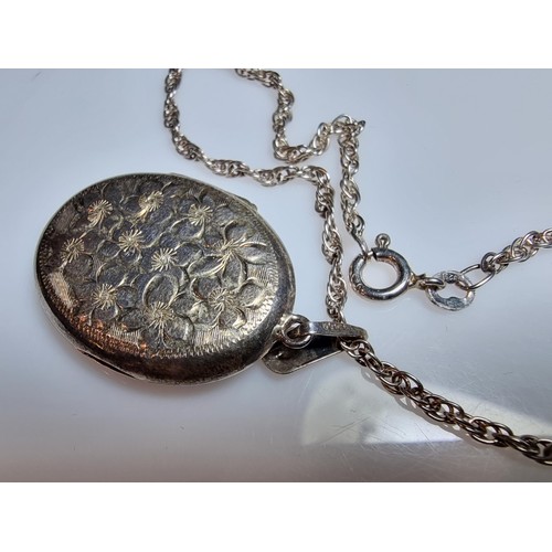 224 - A heavy 925 silver locket with an engraved flower design, complete with its glass inserts, set on a ... 