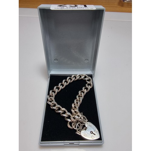 231 - A good quality heavy 1 troy oz hallmarked silver curb link bracelet with a large silver padlock char... 