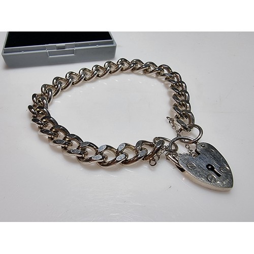 231 - A good quality heavy 1 troy oz hallmarked silver curb link bracelet with a large silver padlock char... 