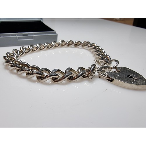 231 - A good quality heavy 1 troy oz hallmarked silver curb link bracelet with a large silver padlock char... 