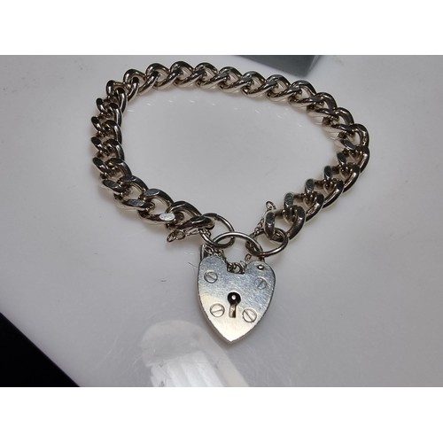 231 - A good quality heavy 1 troy oz hallmarked silver curb link bracelet with a large silver padlock char... 