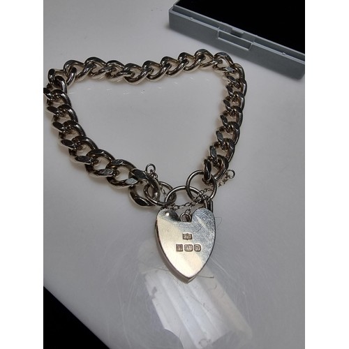 231 - A good quality heavy 1 troy oz hallmarked silver curb link bracelet with a large silver padlock char... 