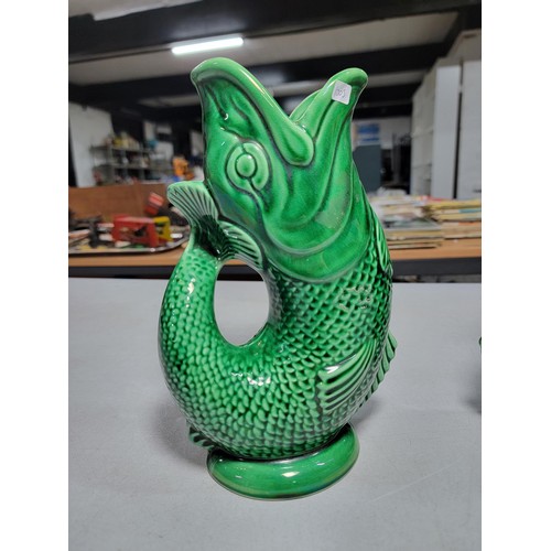 306 - 2x large green fish formed Darmouth Devon glug jugs, one has damage to the base height 24cm