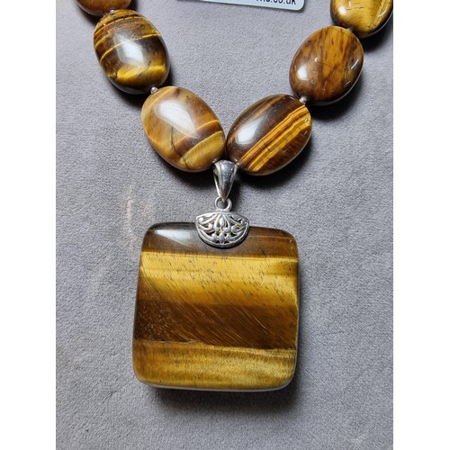 183 - A large impressive tigers eye beaded necklace with a large square tigers eye pendant presenting exce... 