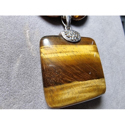 183 - A large impressive tigers eye beaded necklace with a large square tigers eye pendant presenting exce... 