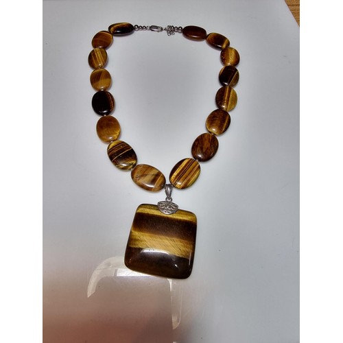 183 - A large impressive tigers eye beaded necklace with a large square tigers eye pendant presenting exce... 