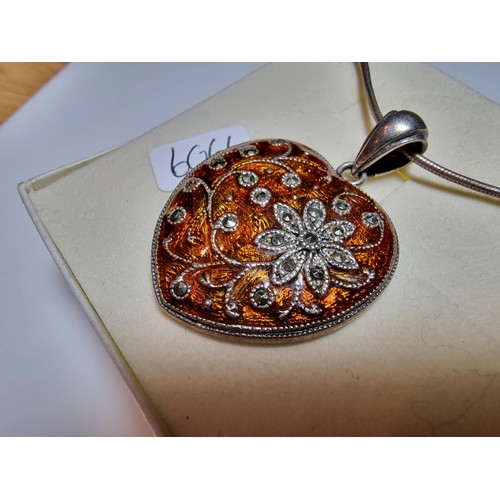 196 - A pretty 925 silver heart shaped pendant with an orange enamelled design inset with marcasite stones... 