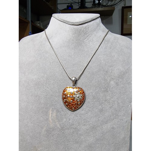 196 - A pretty 925 silver heart shaped pendant with an orange enamelled design inset with marcasite stones... 