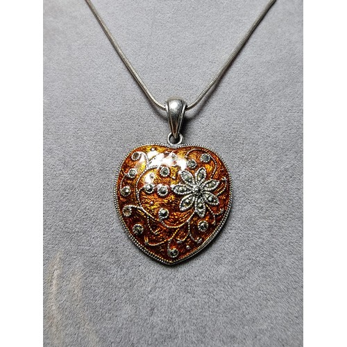 196 - A pretty 925 silver heart shaped pendant with an orange enamelled design inset with marcasite stones... 