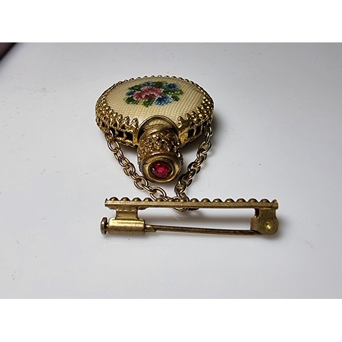 201 - A pretty vintage gilt scent bottle brooch with an ornate design having an embroidered floral scene t... 