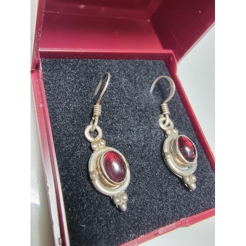 213 - A pair of pretty 925 silver drop earrings inset with garnet stones presenting a vibrant red colour, ... 