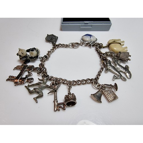 219 - A 925 silver charm bracelet containing 11 charms. A couple of the charms are silver however the rest... 