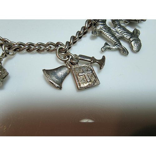 219 - A 925 silver charm bracelet containing 11 charms. A couple of the charms are silver however the rest... 