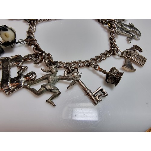 219 - A 925 silver charm bracelet containing 11 charms. A couple of the charms are silver however the rest... 