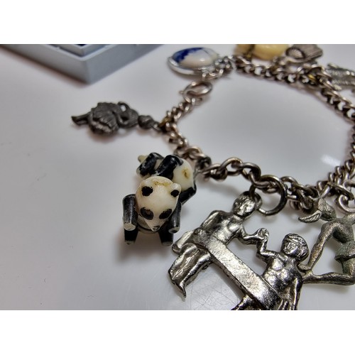 219 - A 925 silver charm bracelet containing 11 charms. A couple of the charms are silver however the rest... 