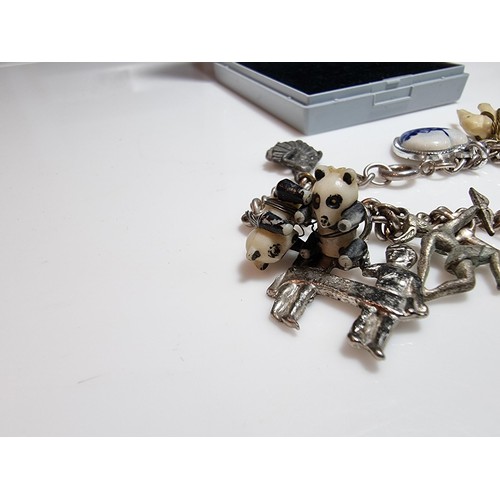 219 - A 925 silver charm bracelet containing 11 charms. A couple of the charms are silver however the rest... 