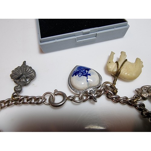 219 - A 925 silver charm bracelet containing 11 charms. A couple of the charms are silver however the rest... 