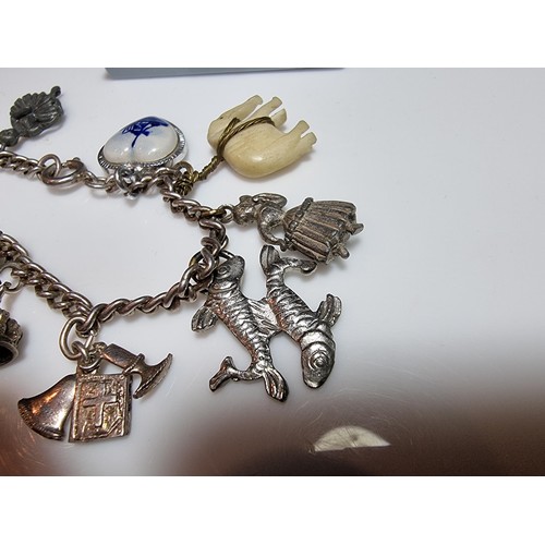 219 - A 925 silver charm bracelet containing 11 charms. A couple of the charms are silver however the rest... 