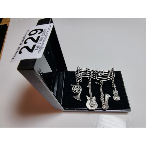 229 - An unusual music related pewter brooch featuring 4 drops which are different instruments presented o... 