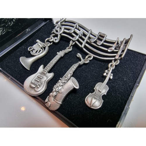 229 - An unusual music related pewter brooch featuring 4 drops which are different instruments presented o... 