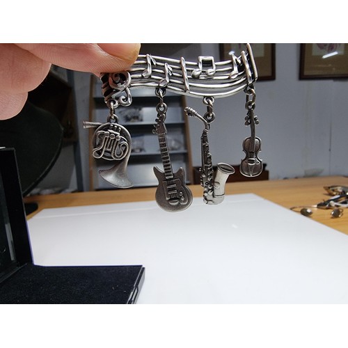 229 - An unusual music related pewter brooch featuring 4 drops which are different instruments presented o... 