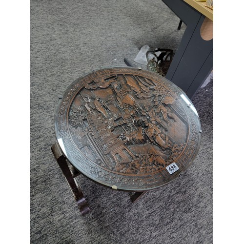 488 - Hand carved camphor wood round table with glass top and of a gate leg variety. Having detailed carvi... 