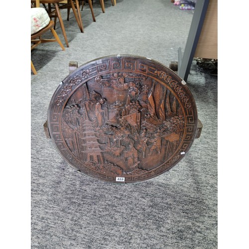 488 - Hand carved camphor wood round table with glass top and of a gate leg variety. Having detailed carvi... 