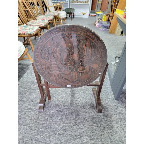 488 - Hand carved camphor wood round table with glass top and of a gate leg variety. Having detailed carvi... 