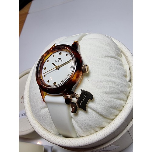 241 - A ladies unused Radley watch with faux tortoise shell case and a white strap featuring a Radley dog ... 