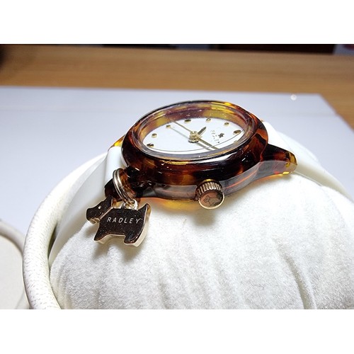 241 - A ladies unused Radley watch with faux tortoise shell case and a white strap featuring a Radley dog ... 