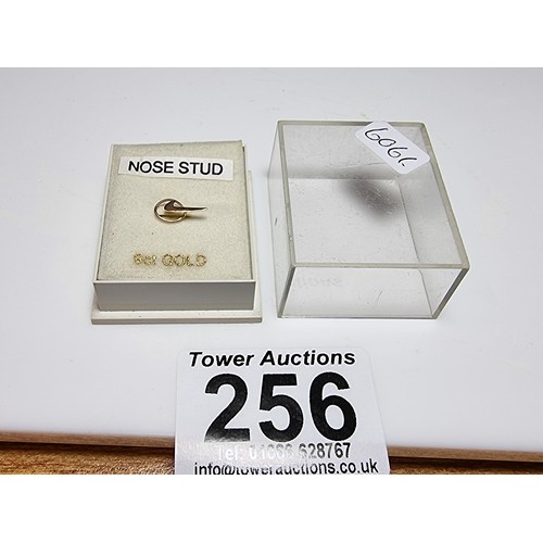 256 - A 9ct yellow gold nose stud in the form of a Nike tick trademark, in as new condition, never been us... 