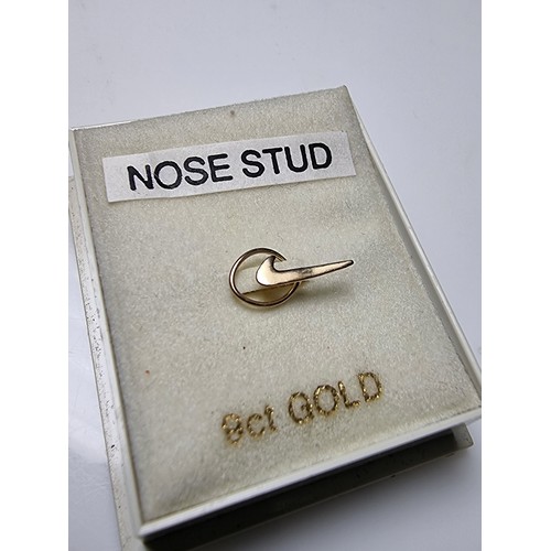 256 - A 9ct yellow gold nose stud in the form of a Nike tick trademark, in as new condition, never been us... 