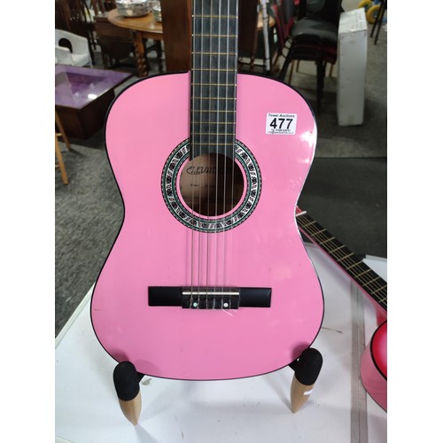 477 - 2x pink acoustic guitars inc an elevation guitar and one other, along with a good quality guitar sta... 