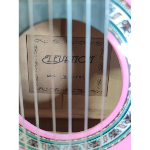 477 - 2x pink acoustic guitars inc an elevation guitar and one other, along with a good quality guitar sta... 