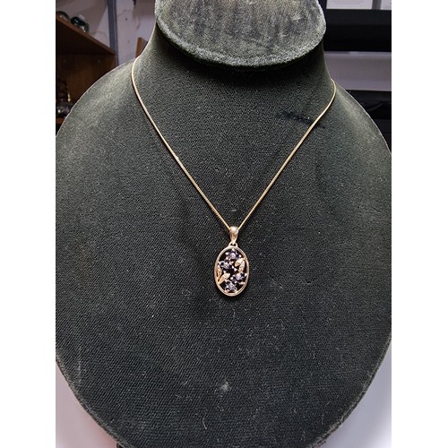 271 - Pretty hallmarked 9ct. yellow gold pendant inset with blue sapphire and diamond stones in a floral d... 