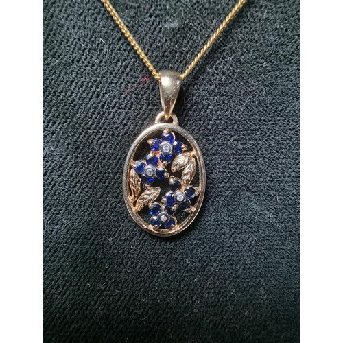 271 - Pretty hallmarked 9ct. yellow gold pendant inset with blue sapphire and diamond stones in a floral d... 