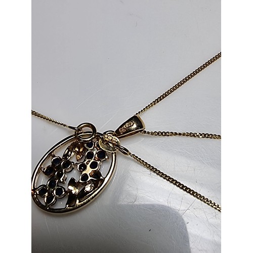 271 - Pretty hallmarked 9ct. yellow gold pendant inset with blue sapphire and diamond stones in a floral d... 