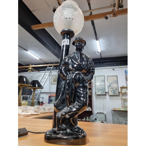 301 - Tall black figural lamp in the form of a gentleman standing by a lamp post. having a glass shade. In... 