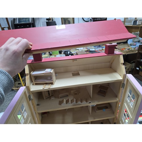 61 - A large pink painted wooden dolls house complete with a quantity of wooden dolls house furniture for... 