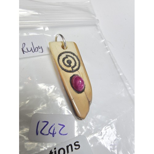 199 - An ancient fossilized Walrus tusk carved pendant inset with a genuine opaque ruby showing a vibrant ... 