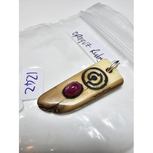 199 - An ancient fossilized Walrus tusk carved pendant inset with a genuine opaque ruby showing a vibrant ... 