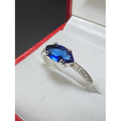204 - A pretty 925 silver ring inset with a large blue CZ crystal with smaller clear CZ crystal stones to ... 
