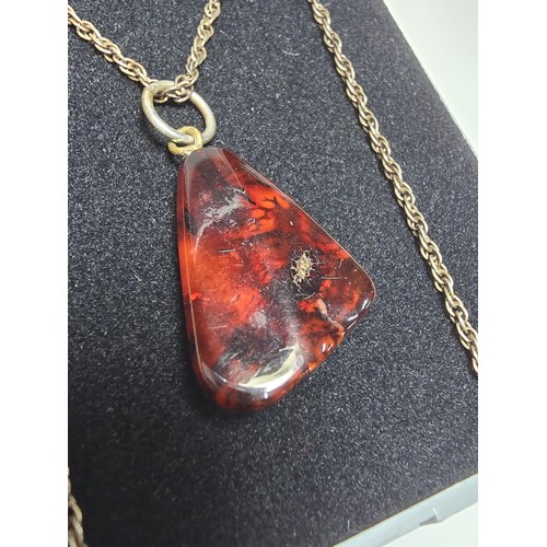 215 - A stunning deep red genuine amber pendant which displays very nicely with light shining through it. ... 