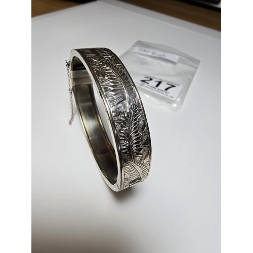 217 - A sterling silver hinged bangle with an engraved fern leaf sign, in clean condition, appears unmarke... 