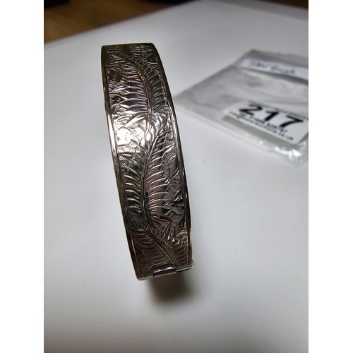 217 - A sterling silver hinged bangle with an engraved fern leaf sign, in clean condition, appears unmarke... 